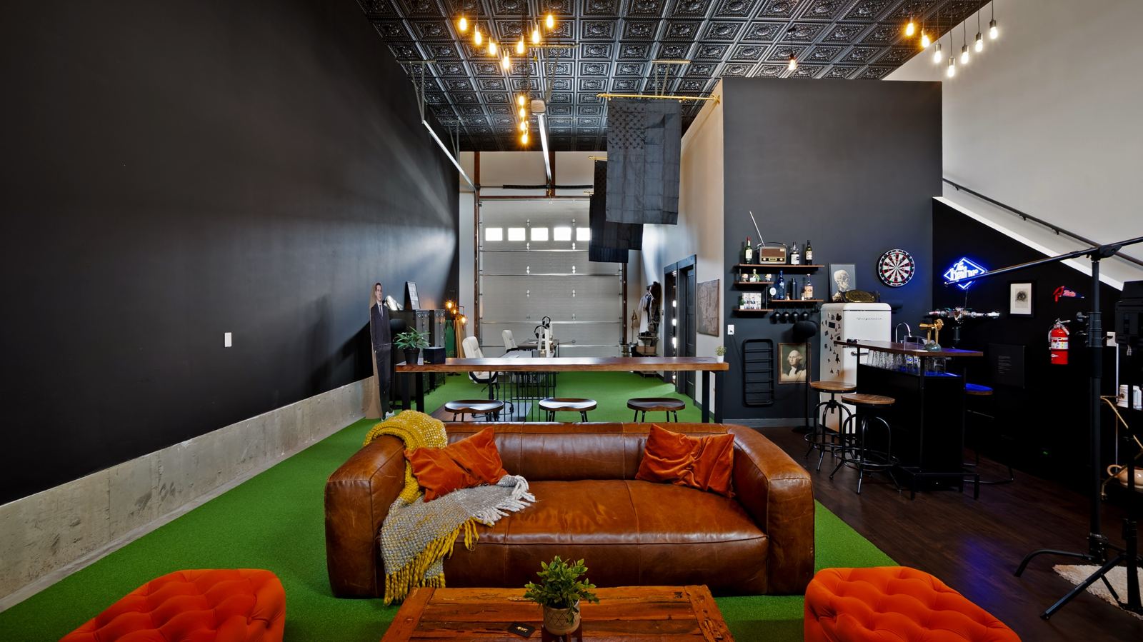 The bahlr HQ lounge with a leather sofa, bar and hanging Edison bulbs